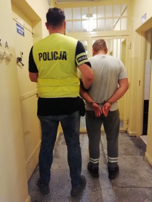 nieumundurowany policjant w kamizelce z napisem policji z zatrzymanym mężczyzną