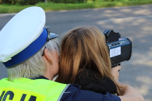 Policjnatka wraz z dziewczynką mierzy prędkość pojazdu.