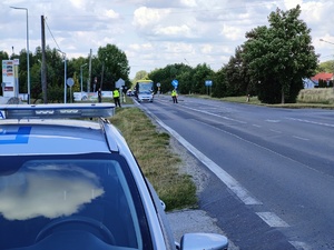 Na skrzyżowaniu stoją policjanci, którzy wstrzymują ruch pojazdów.