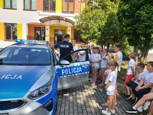 Policjnat opowiada dzieciom o wyposażeniu radiowozu.