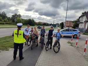 Policjantka rozmawia z młodymi rowerzystami o bezpieczeństwie na drodze.
