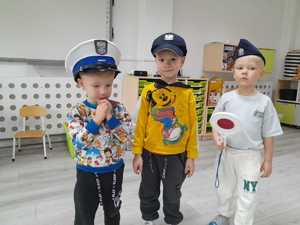 Dzieci pozują do zjęcia. Mają ubrane czapki policyjne.