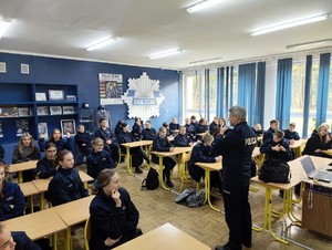 Naczelnik Wydziału Doboru stoi na środku klasy i opowiada uczniom o pracy policjanta.