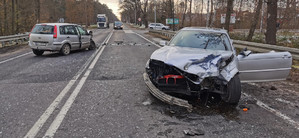 Przód rozbitego samochodu marki BMW. W tle uszkodzony samochód marki Ford.
