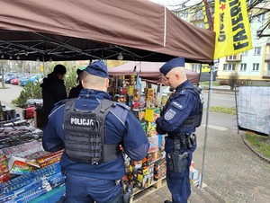 Policjanci kontrolują stoisko sprzedaży fajerwerków.