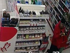 Wizerunek sprawcy kradzieży sklepowej. Mężczyzna trzyma czerwony koszyk zakupowy w dłoni.