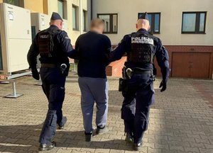 Policjanci prowadzą zatrzymanego.