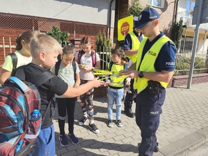 Policjanci rozdają elementy odblaskowe dzieciom.