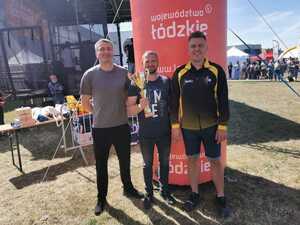 Trzech policjnactów pozuje do zdjęcia trzymając puchar za pierwsze miejsce.