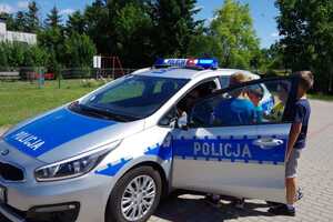 Policjant siedzący w radiowozie prezentuje działanie świateł błyskowych.