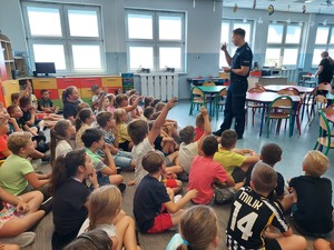 Policjant rozmawia z uczniami klas drugich i trzecich o bezpieczeństwie podczas drogi do szkoły.