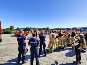 Liczna grupa strażaków oraz policjanci omawiają szczegóły zaplanowanych ćwiczeń.