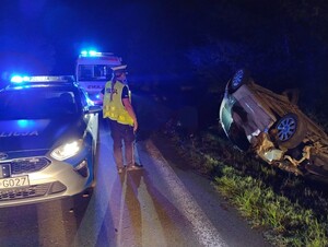 Policjantka Wydziału Ruchu Drogowego patrzy na leżący na dachu samochód.