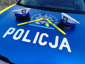 Na masce policyjnego radiowozu leżą czapki policyjne i odblaski.