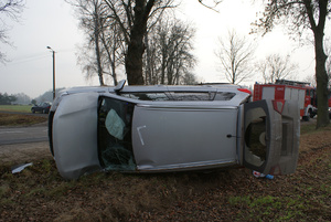 Samochód koloru srebrnego leżący na boku.