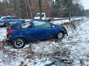 Uszkodzony pojazd marki Opel stoi poza drogą, w tle widać policyjny radiowóz.