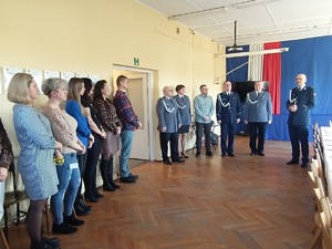 Policjanci w mundurach oraz osoby cywilne stojąca po lewej stronie