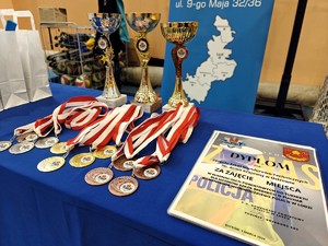 Medale, puchary oraz dyplomy leżące na stole.