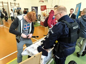 Uczeń składa policyjną broń palną. Czynność nadzoruje policjant.