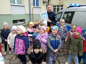 Grupowe zdjęcie. Policjant trzyma w dłoniach podziękowanie.