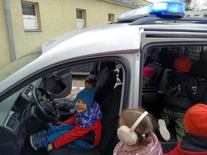 Dzieci siedzą w policyjnym radiowozie.