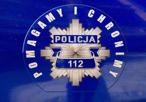 Policyjne logo a wokół niego napis &quot;pomagamy i chronimy&quot; oraz numer alarmowy 112.