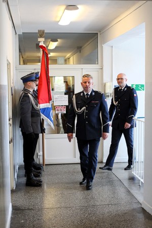 Pierwszy Zastępca Komendanta Wojewódzkiego Policji w Łodzi jest wprowadzany przez Komendanta Powiatowego Policji w Łasku. Po lewej stronie stoi poczet sztandarowy łaskich policjantów.