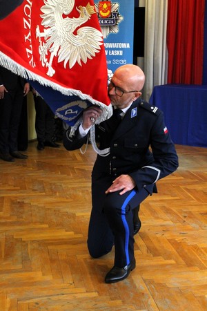 Komendant Powiatowy Policji w Łasku wita się ze sztandarem jednostki.