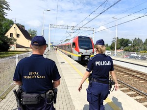 Policjantka wraz z funkcjonariuszem Straży Ochrony Kolei patroluje dworzec kolejowy.