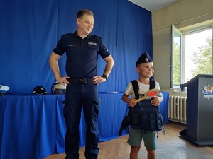 Policjant pozuje do zdjęcia z chłopcem w stroju policjanta.