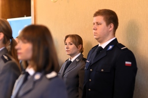 Zdjęcie przedstawia policjanta i policjantkę stojących w szeregu.