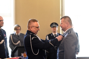 Zastępca Komendanta Wojewódzkiego Policji w Łodzi przypina policjantowi do munduru  odznakę &quot;Zasłużony Policjant&quot;.