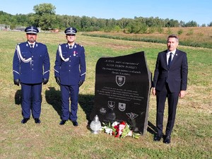 Komendant Powiatowy Policji w Łasku wraz ze swoim zastępcą i Prezesem Stowarzyszenia &quot;Rodzina Policyjna&quot; pozują do zdjęcia przy pamiątkowej tablicy.