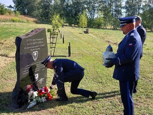 Komendant Powiatowy Policji w Łasku wraz ze swoim zastępcą oraz Prezesem Stowarzyszenia &quot;Rodzina Policyjna&quot; składają kwiaty przy pamiątkowej tablicy.