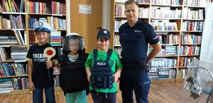 Policjant wraz z dziećmi w sprzęcie policyjnym pozują do zdjęcia.