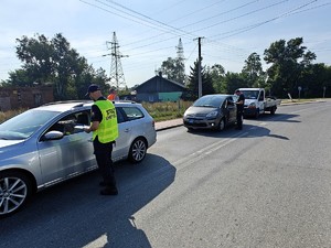 Polcjant wraz z funkcjonariuszem Straży Ochrony Kolei rozdaje ulotki informacyjne.