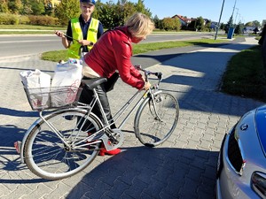 Policjantka rozdaje oblaski rowerzystą.