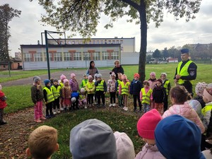 Policjant stoi przed dziećmi i rozmawia z nimi o bezpieczeństwie.