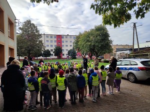 Policjant stoi przed dziećmi i rozmawia z nimi o bezpieczeństwie.