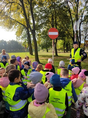 Policjant stoi przed dziećmi i rozmawia z nimi o bezpieczeństwie.