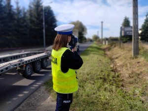 Policjanta kontroluje prędkość poruszających się drogą pojazdów.