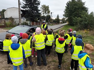 Dzieci stoją przy samochodzie i recytują wierszyk.