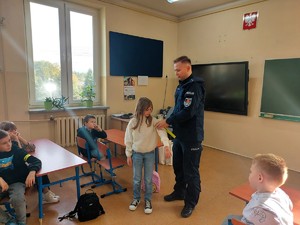 Policjant zakłada odblask na ramię dziewczynki.