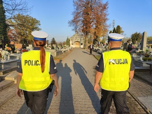 Policjanci idą cmentarną ścieżką.