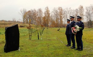 Policjanci w mudnurach galowych stoją przed pamiątkową tablicą.