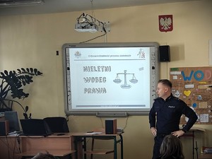 Policjant stoi przed ekranem projektora. Na ekranie wyświetla się napis &quot;Nieletni wobec prawa&quot;.