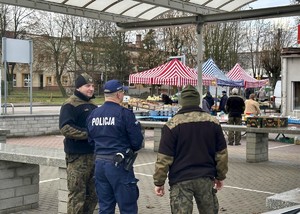 Policjant wraz ze funkcjonariuszami straż rybackiej na targowisku w Łasku.