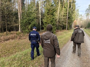 Polcijant wraz z funkcjonariuszami straży granicznej patrolują dukty leśne.