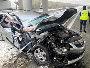 Uszkodzony pojazd, w tle pracująca policjantka.