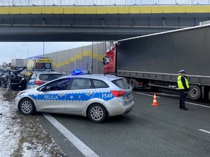 Policyjne radiowozy. Policjantka kieruje ruchem. W tle samochód ciężarowy.